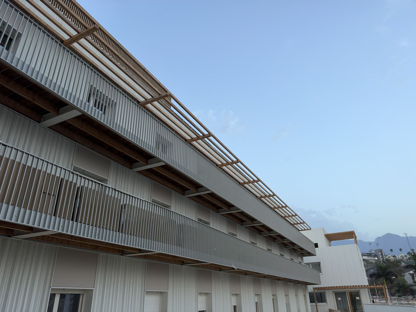 Fachada de la residencia de Adeje con pasarelas y pérgola de madera