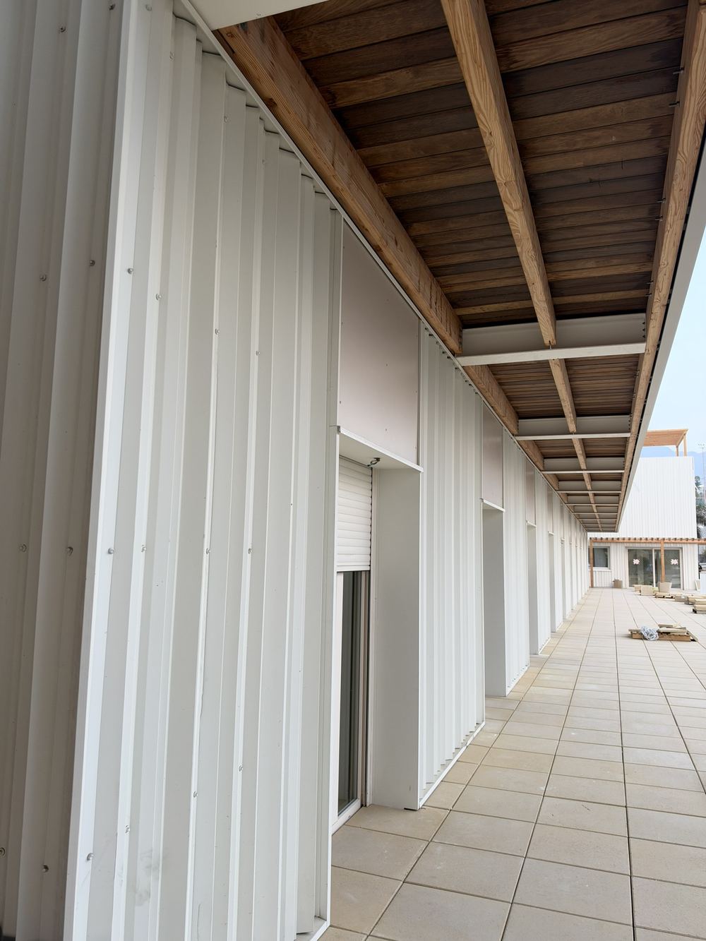 Galería exterior de la residencia de Adeje con techo de madera y fachada metálica